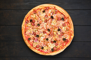 Pizza with various kind of thin sausages, pickled cucumber, olives and onion