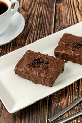 Chocolate covered raisin cake on wooden table with filter coffee