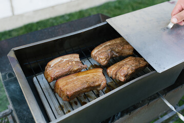 Bacon is smoked in a metal smokehouse in the open air