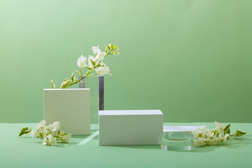 A front view of white and transparent podium decorated with flower and green background with blank space for advertising 