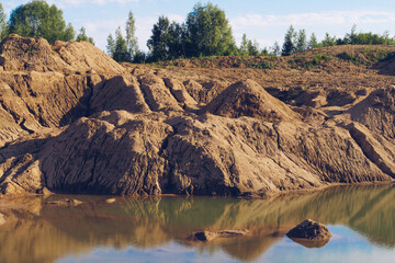 Flooded sand quarry. Cracked drought clay piles during the dry season. Bright yellow or orange...