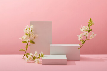 A front view of white podium decorated with flower and pink background with blank space for advertising 
