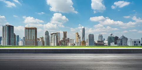 Side view of asphalt road highway with green grass and modern city skyline