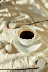 Cup of coffee in bed with cotton flowers,  morning mood, Organic and natural linen cotton textile bedclothes, copy space.