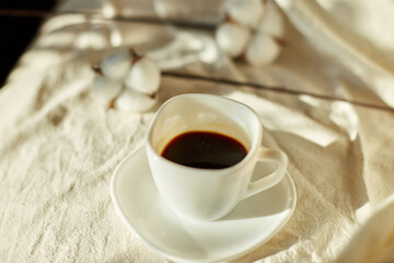 Cup of coffee in bed with cotton flowers,  morning mood, Organic and natural linen cotton textile bedclothes, copy space.