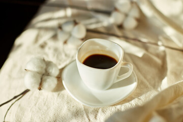 Cup of coffee in bed with cotton flowers,  morning mood, Organic and natural linen cotton textile bedclothes, copy space.