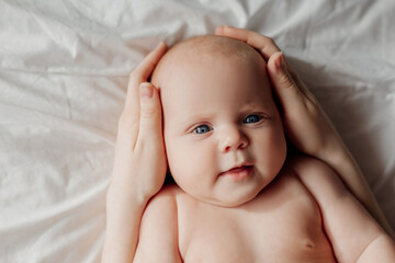 mother holds the baby's head in her hands. cute sweet newborn baby