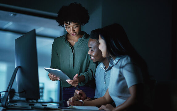 At the core of success is commitment. Shot of a group of young businesspeople using a digital tablet and computer during a late night at work.