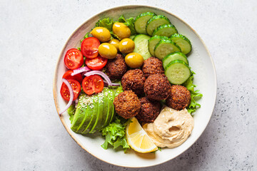 Falafel salad bowl with hummus, olives and vegetables. Healthy vegan food concept.