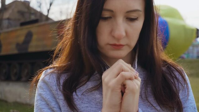 Portrait Ukrainian woman patriot folded her hands and praying in front of developing flag of his country during war for independence and freedom. Crisis, peace, stop aggression in whole world