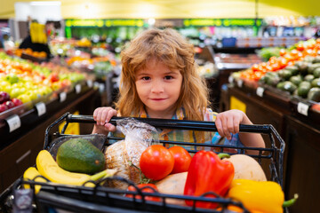 Healthy kids food. Child in supermarket buys vegetables. Kids shopping in supermarket.