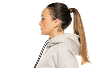a young woman in a gray tracksuit and pony tail posing to a white background in the studio