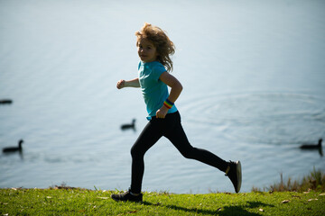 Kids running outdoors. Run and healthy sport for children. Child running on summer field near lake, kids fitness. Running training outdoor, morning jogging. Children athletes.