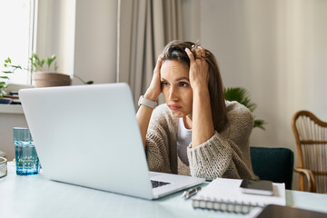 Stressed freelancer looking at laptop working from home