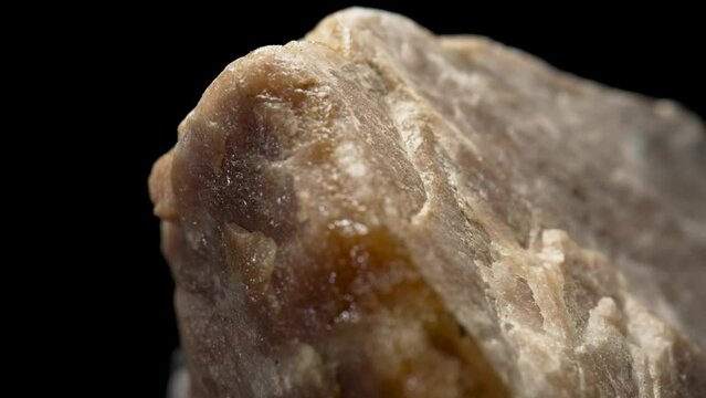 Solid piece of granite or quartz stone against black background. Natural rough mineral. Background of natural structure of stone. Concept of geology, ore mining, building material. Macro close up.