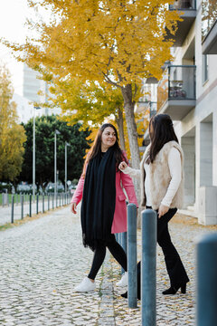 Sisters walking on footpath in front of building