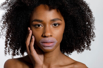 Young woman with lip mask against white background