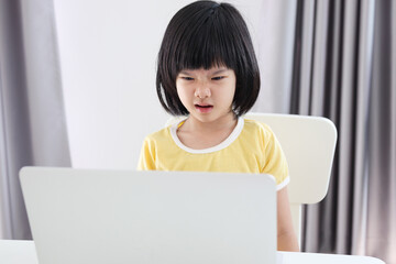 little asian girl student study online using laptop computer at home
