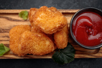 Meat nuggets with ketchup on a dark background