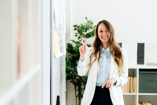 Smiling businesswoman holding felt tip pen in office