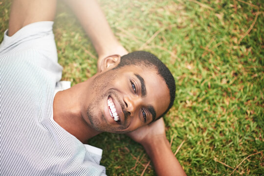Ive been waiting for this moment all week. Shot of a young man relaxing on the grass outdoors.