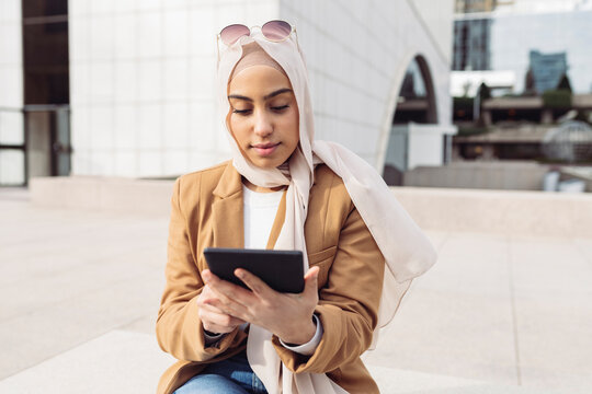 Young businesswoman using tablet PC sitting at office park