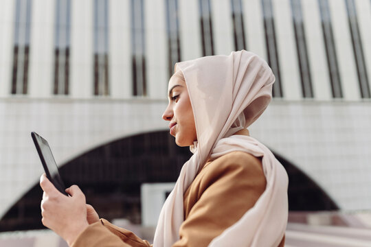 Young businesswoman using tablet PC in front of building