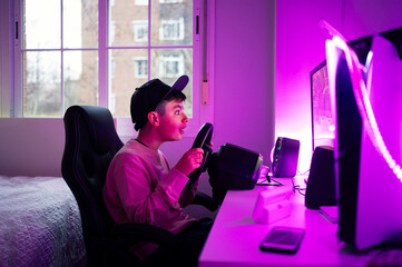 Surprised boy playing video game on computer in bedroom at home
