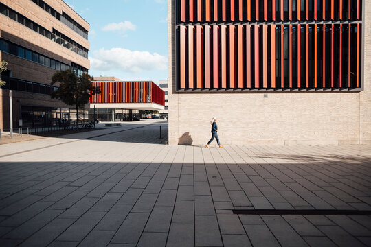 Businesswoman walking outside office building on sunny day