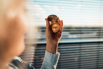 Businesswoman holding navigational compass in office