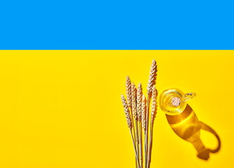 Ears of wheat by oil bottle on blue and yellow Ukrainian flag