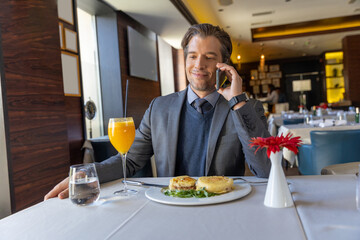 Businessman talking on the smartphone while having breakfast in the restaurant
