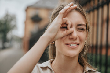 Smiling young woman winking eye gesturing OK sign