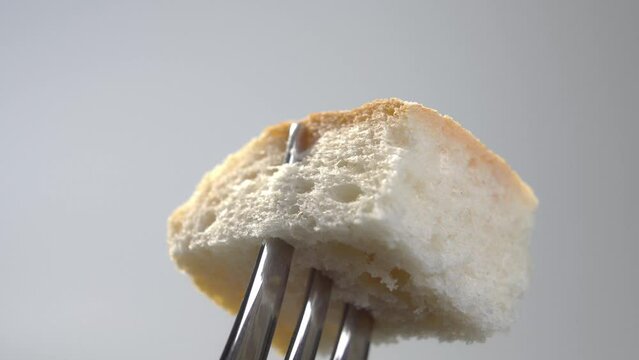 A piece of wheat bread with a crispy crust on a fork close-up. Macro. Rotation
