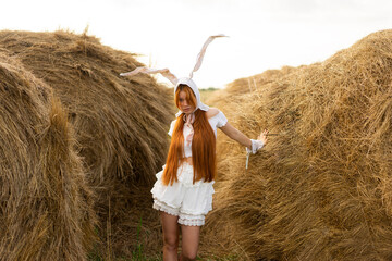Young woman wearing rabbit costume ears standing amidst hay bales