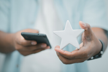 Satisfaction concept mobile. Businessman holding a white star showing satisfaction while working at home or at work. , online marketing , planning , leadership , stock trading

