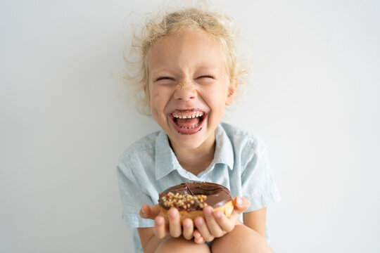 Cheerful girl holding doughnut and laughing