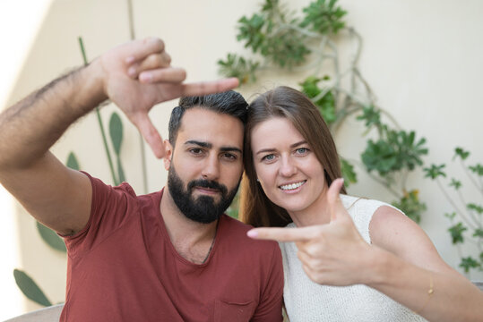 Heterosexual couple making finger frame in back yard
