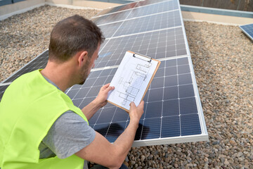 Engineer examining solar panels with blueprint