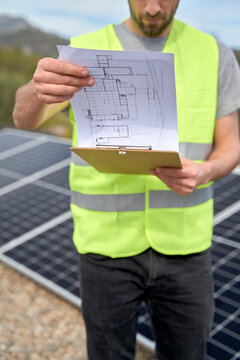Engineer examining blueprint of solar panels