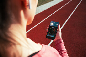Fitness app. Smart phone screen with fitness health or sport gym mobile application. Girl holding app for training indoors.