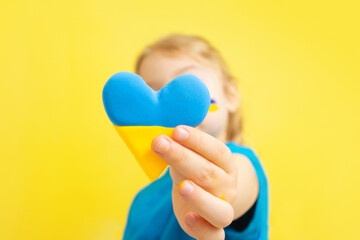 The girl holds a heart of yellow and blue color of the Ukrainian flag. Love to Ukraine concept