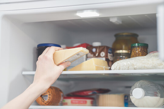 storing cheese in the refrigerator. the woman takes cheese out of the refrigerator.