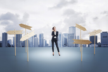 Attractive young european businesswoman standing on blurry city background with wooden pointers....