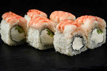 Sushi rolls Philadelphia with snow crab, cream cheese, cucumber, sesame seeds isolateed on black background. Japanese oriental cuisine