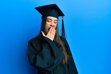 Beautiful brunette young woman wearing graduation cap and ceremony robe bored yawning tired covering mouth with hand. restless and sleepiness.
