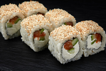 Traditional delicious fresh sushi roll set on a black background. Sushi roll with rice, cream cheese, avocado, salmon, sesame. Philadelphia. Sushi menu. Japanese kitchen, restaurant.