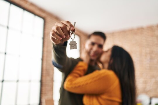 Man and woman couple kissing hugging each other holding key of new house at new home