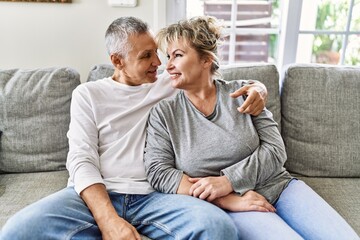 Senior caucasian couple smiling happy and hugging sitting on the sofa at home.