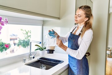 Young blonde woman smiling confident washing jar at kitchen